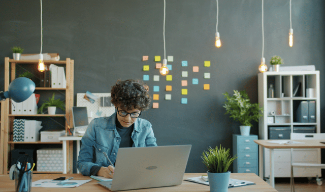 Professional developing incentive program strategy on laptop with colorful planning sticky notes on office wall