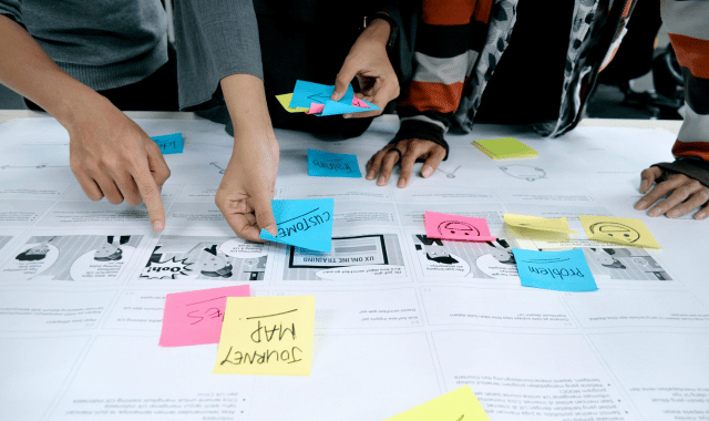 Business team collaborating on incentive program strategy with planning documents and colorful sticky notes